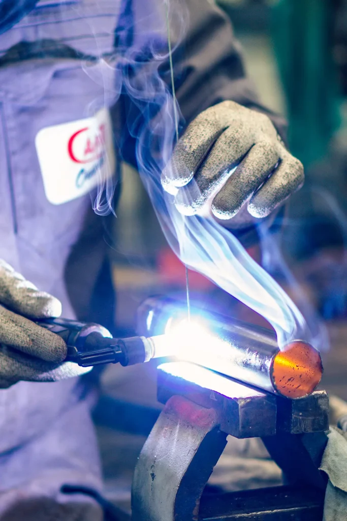 Un soudeur au travail, l'arc TIG sous la flamme bleue.